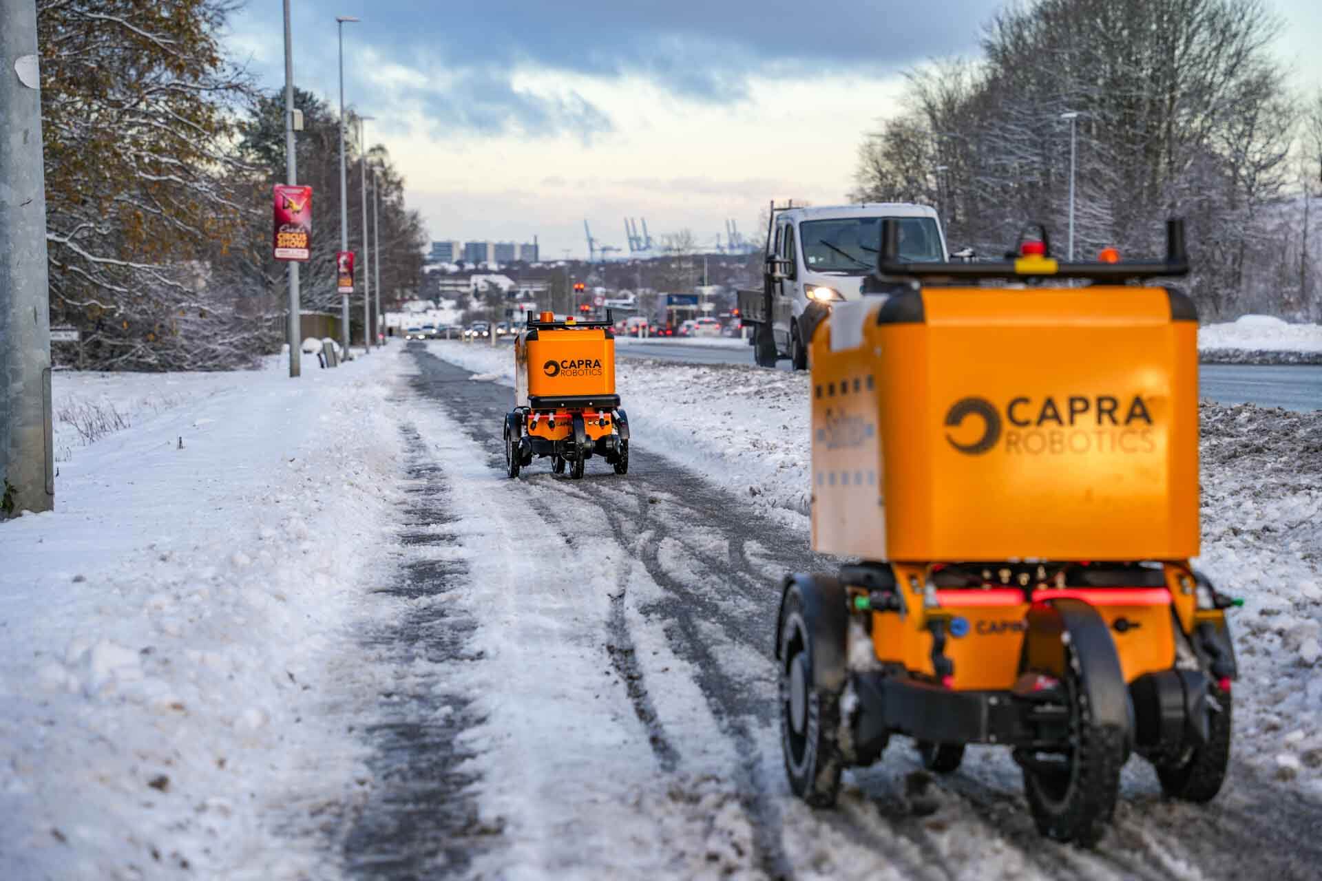 two deicing robots driving by snowy road